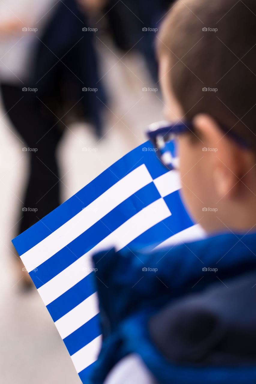 boy with glasses holding greek national flag