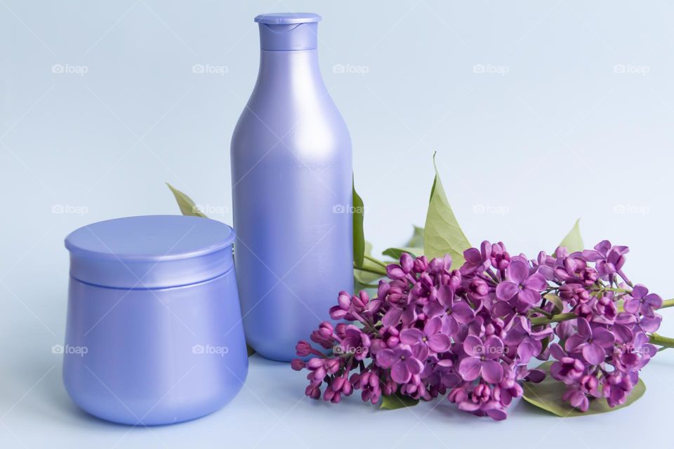 Jars with cosmetic products, beauty cosmetics in purple jars with fragrant flowers.