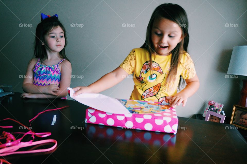 Girl looking at her sister opening gift