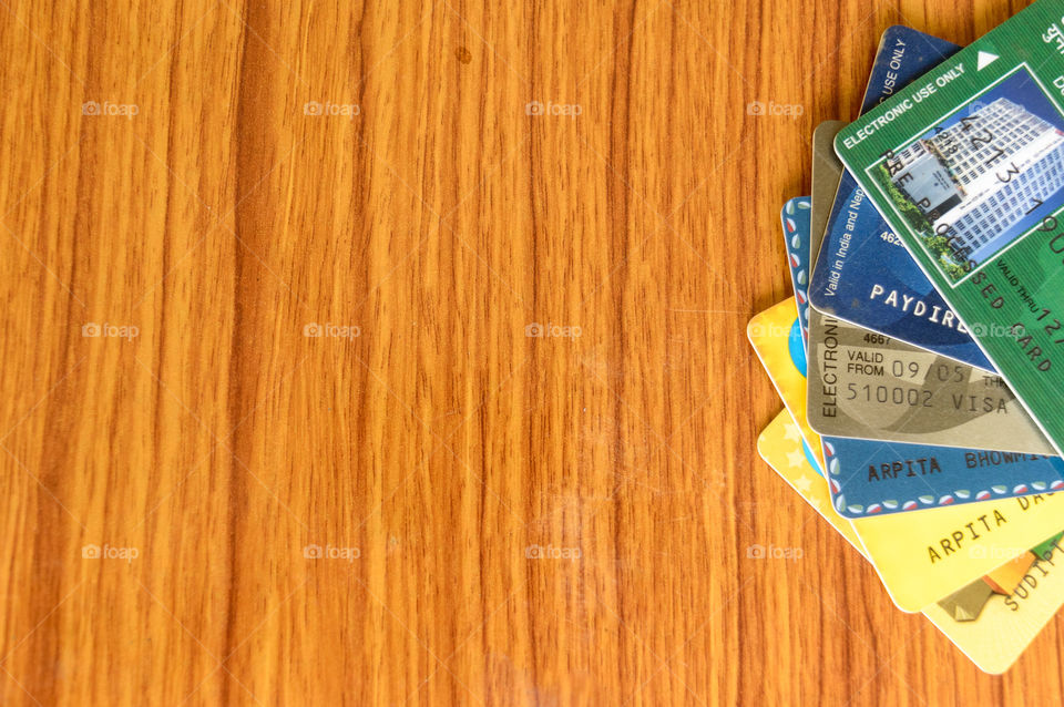 Stack of different bank credit card placed at the edge of wooden table. Business finance economy concept. High angel view with copy space room for text on left side of image.