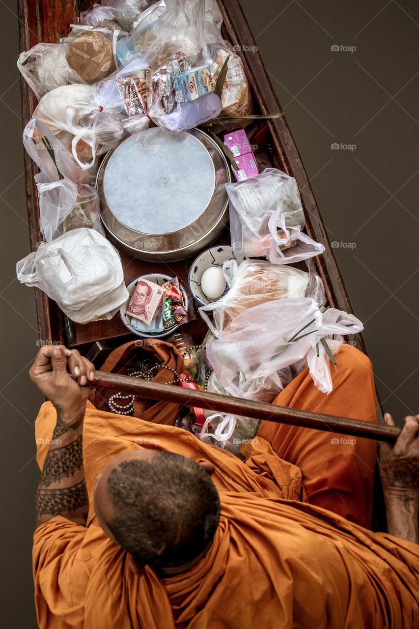 Thai buddhist monk asking for alms in his boat at dawn