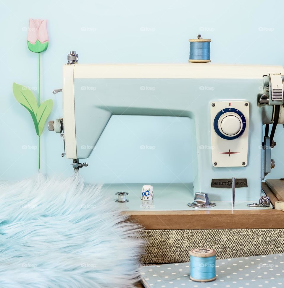 Vintage blue sewing machine, with faux fur, cotton reels and China thimble 