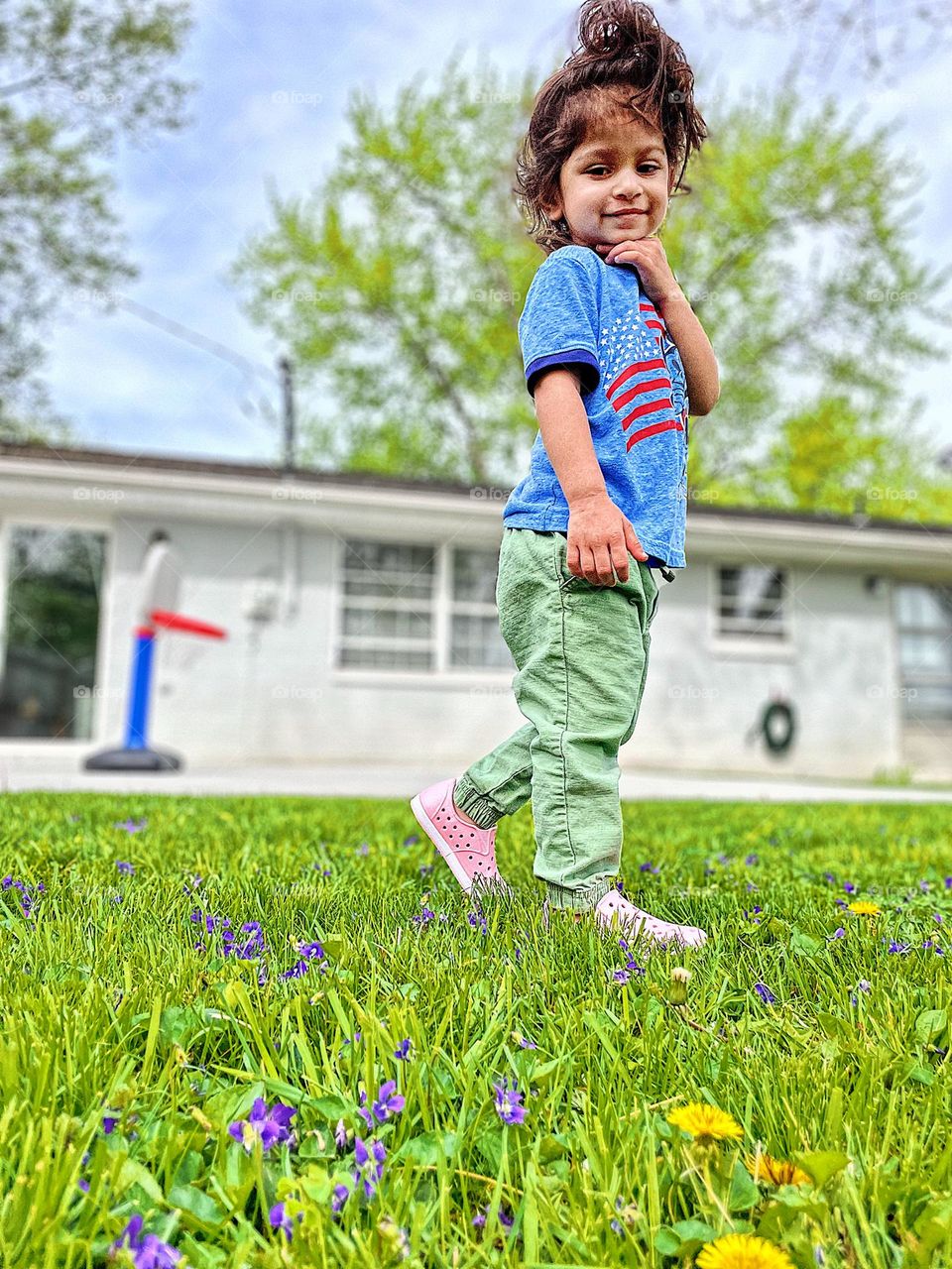 Toddler girl acting like a model in backyard, toddler being silly outside, toddler has fun in the lawn, springtime in Ohio, low perspective 