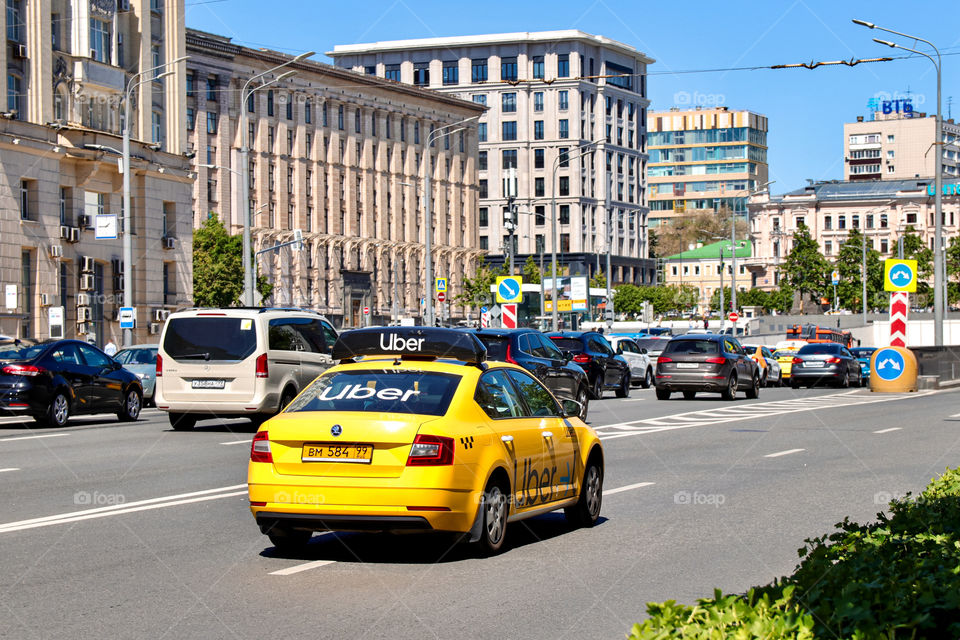 yellow uber taxi driving along the city road