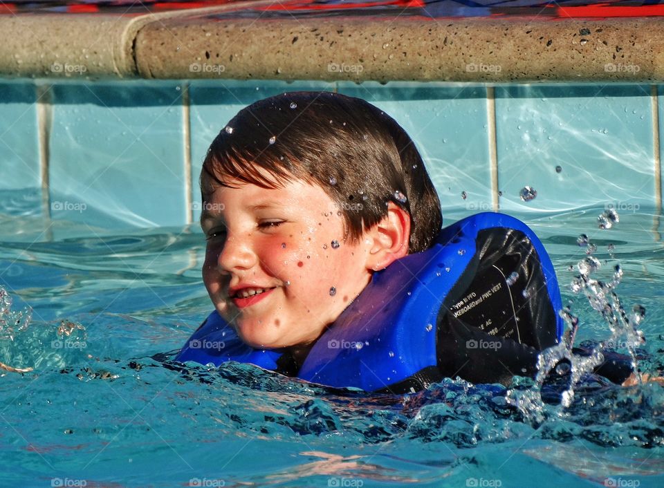 Young Swimmer. Young Boy Wearing Life Jacket Learning To Swim
