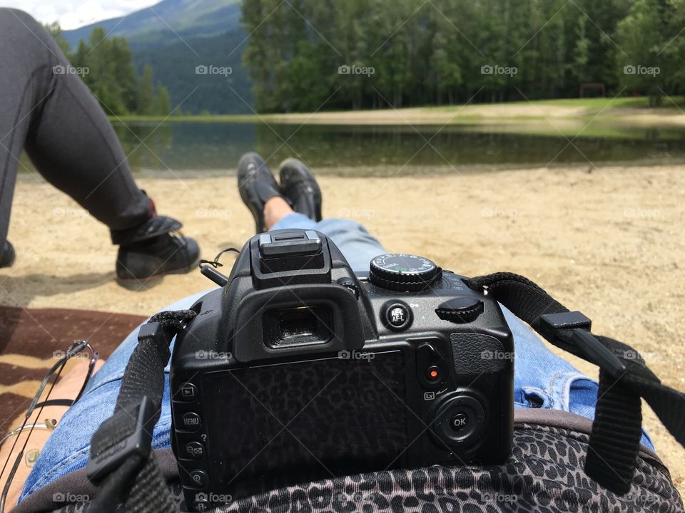 Weary photographer resting with camera on stomach in front of Rocky Mountain scenery