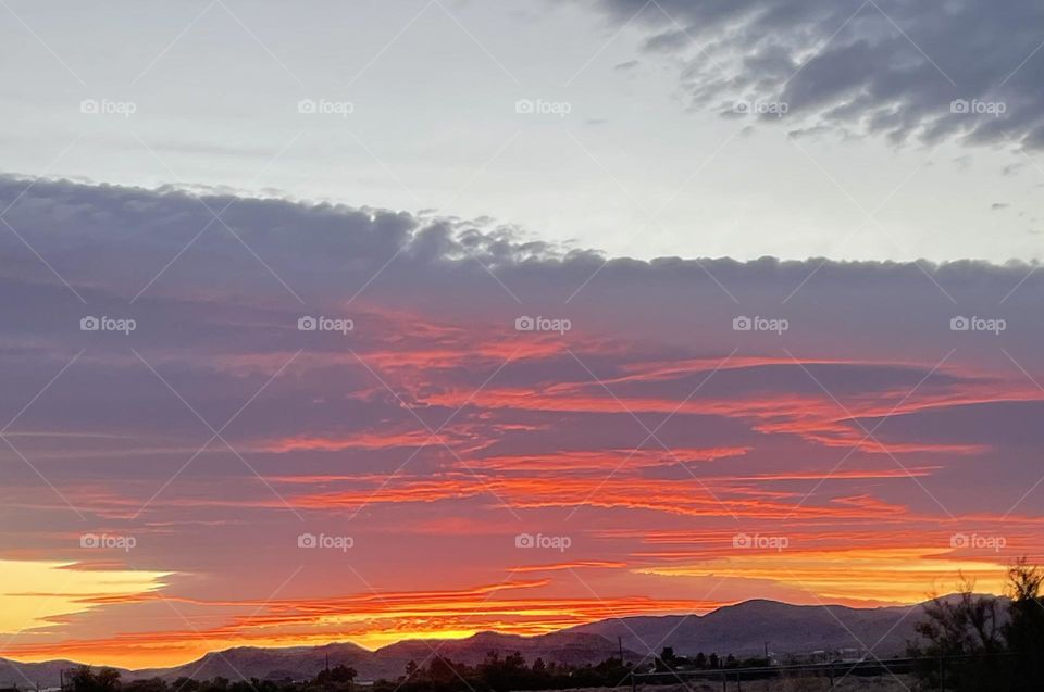 A red, orange, and yellow sunset with mountains. 