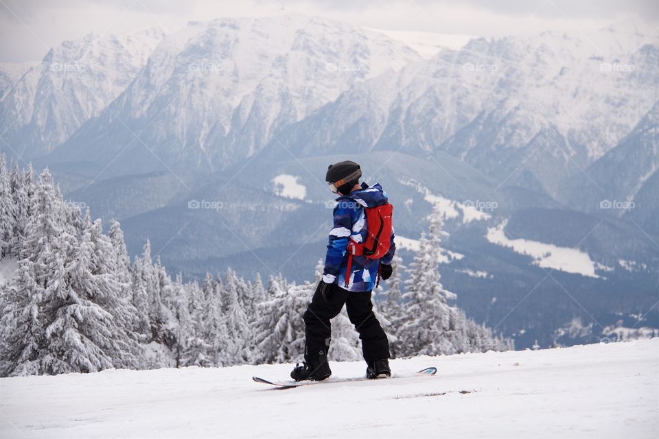 Young man snowboarding in peak Postavarul 