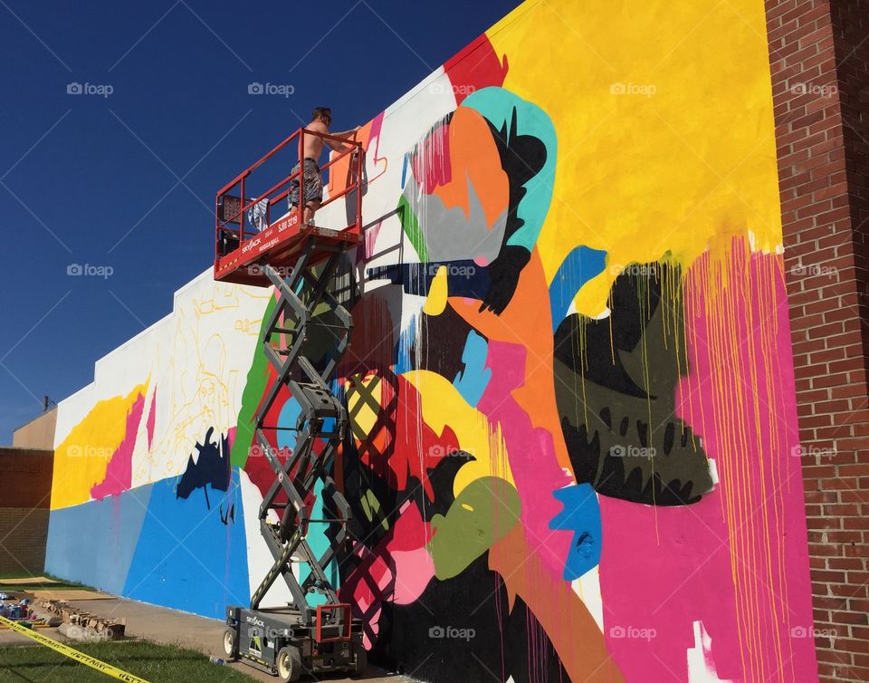 Artist creating a mural on a downtown building