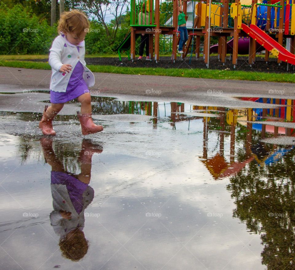 Baby girl runs in the water. 
funny to see the reflection in the water. She use boots because tve bad weather..