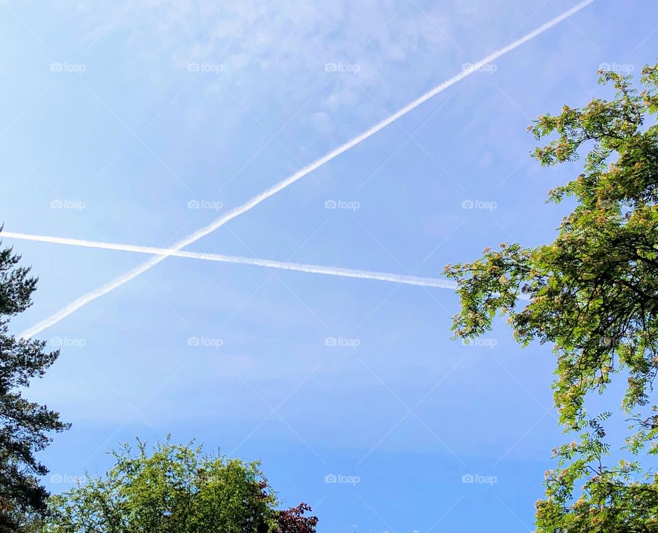 Minimalistic skyscape with two crisscrossed aircraft trails on the blue sky