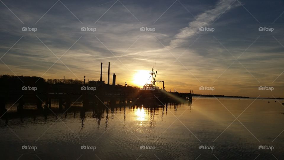 Silhouette of industry near sea during sunset