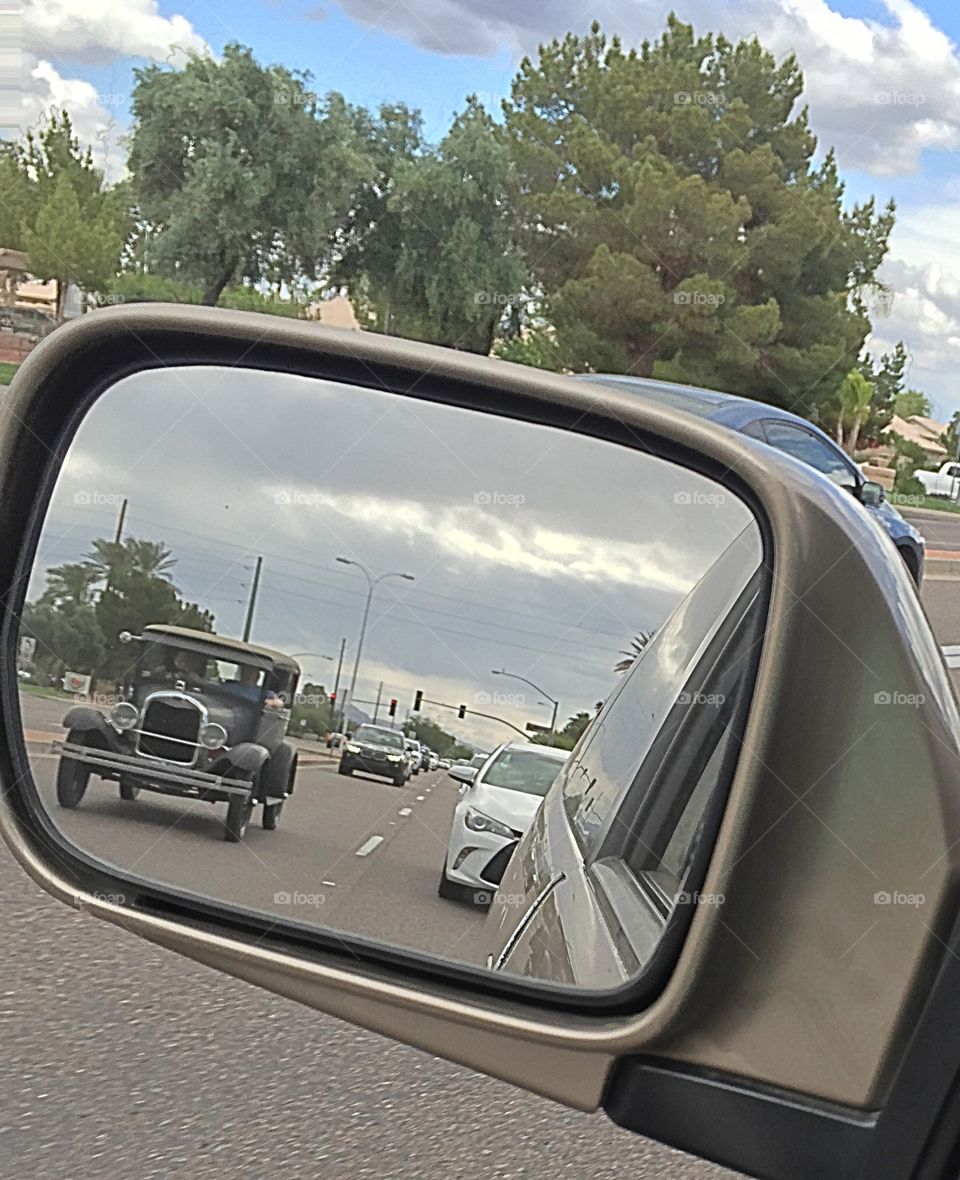 Antique car on the road and view of it from my car mirror