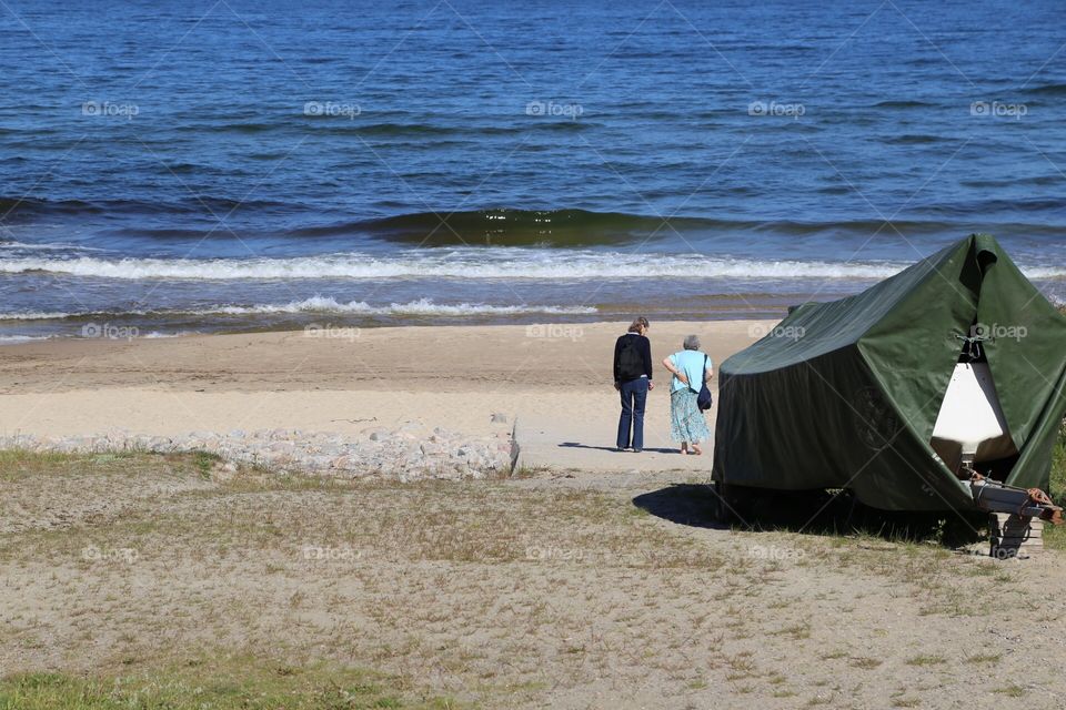 Two people standing on the sandy beach by the ship on land in springtime