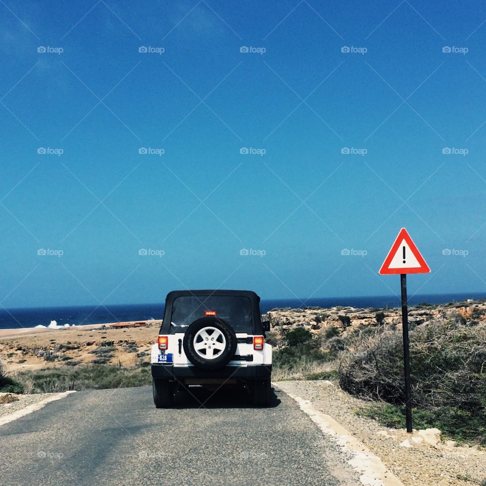 Off-roading in a Jeep through the desert island of Aruba. The beautiful blue sky above, and the ocean in the distance, an adventure awaits. 