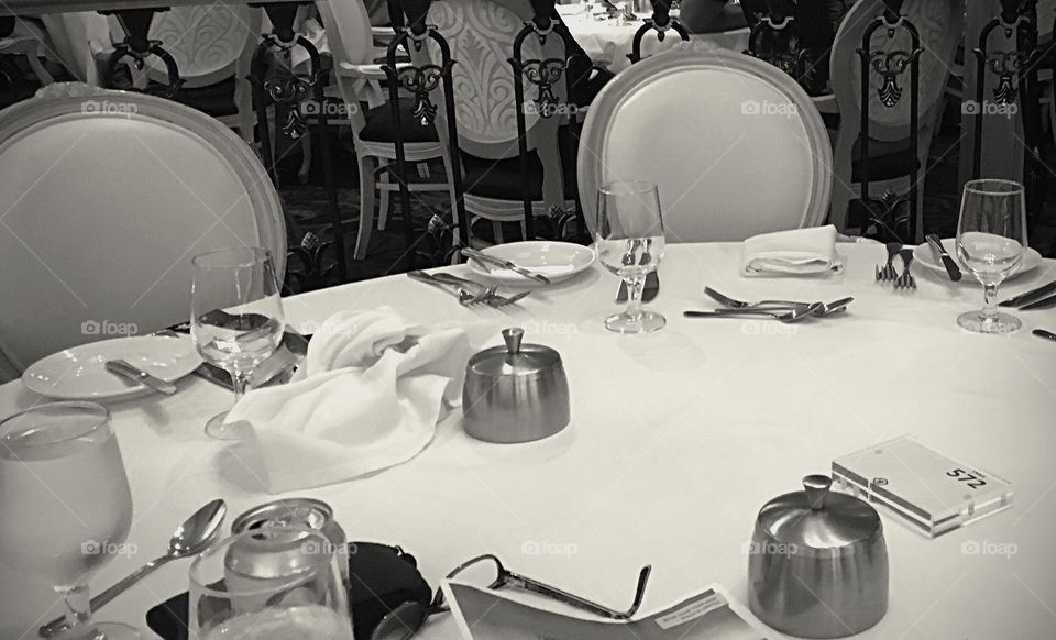 Empty seats at the dinner table.  Black and white photo of empty chairs and table. 