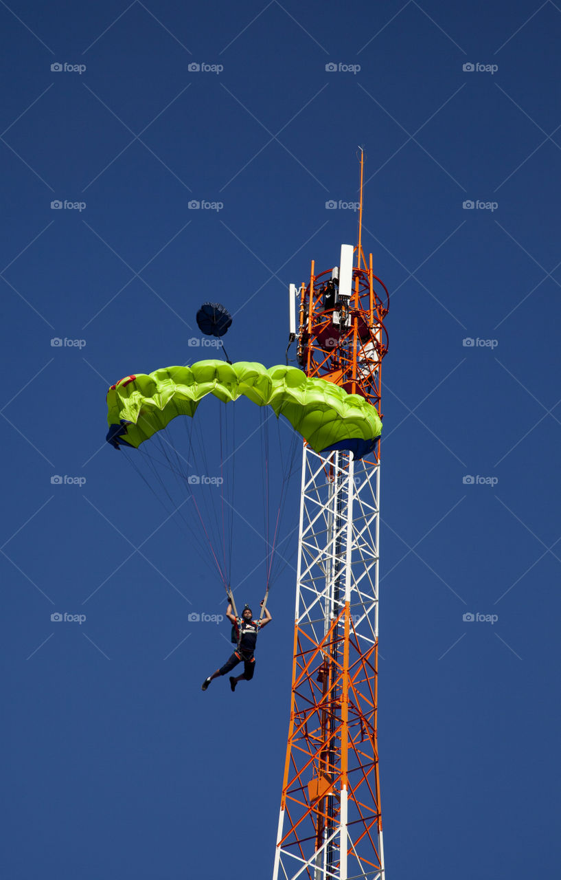 Paragliding in sky with communication tower