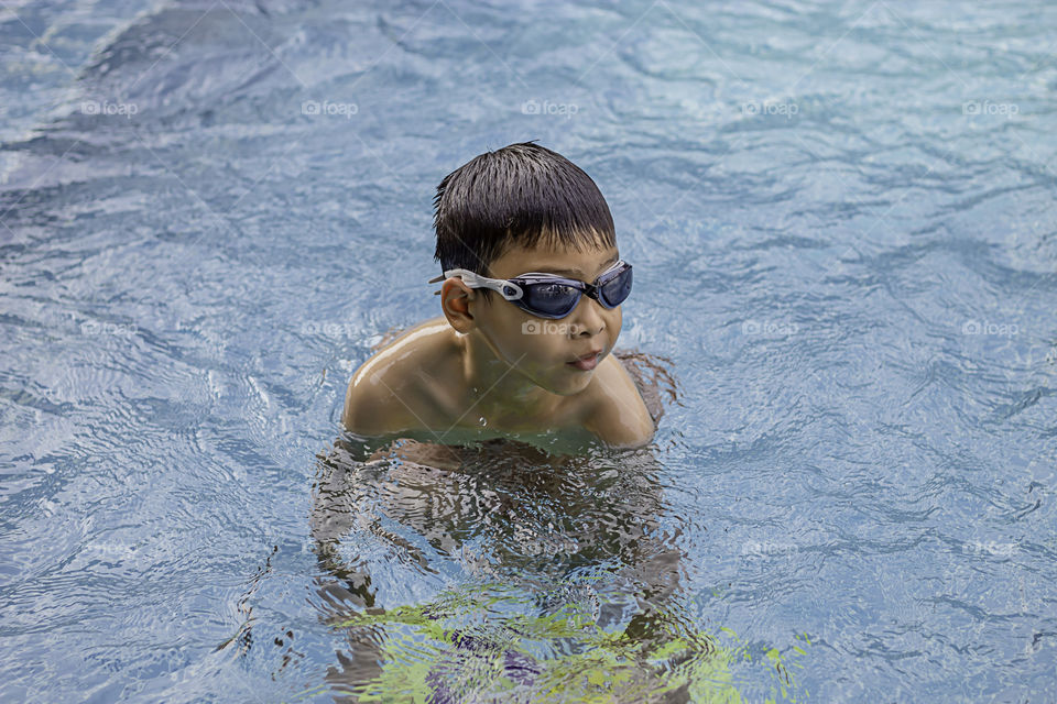 Asian boy learned to swim in the pool.