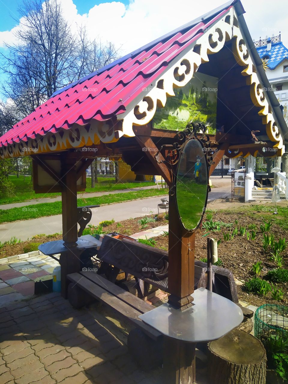 A multi-colored gazebo for relaxing in the park, on which a picture and a mirror hang