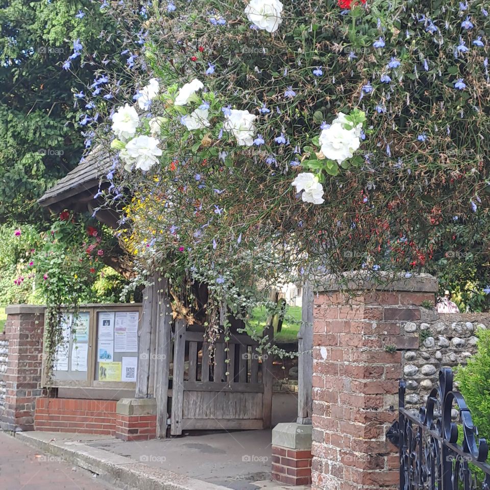 pretty entrance to churchyard flowers roof wall opening gate