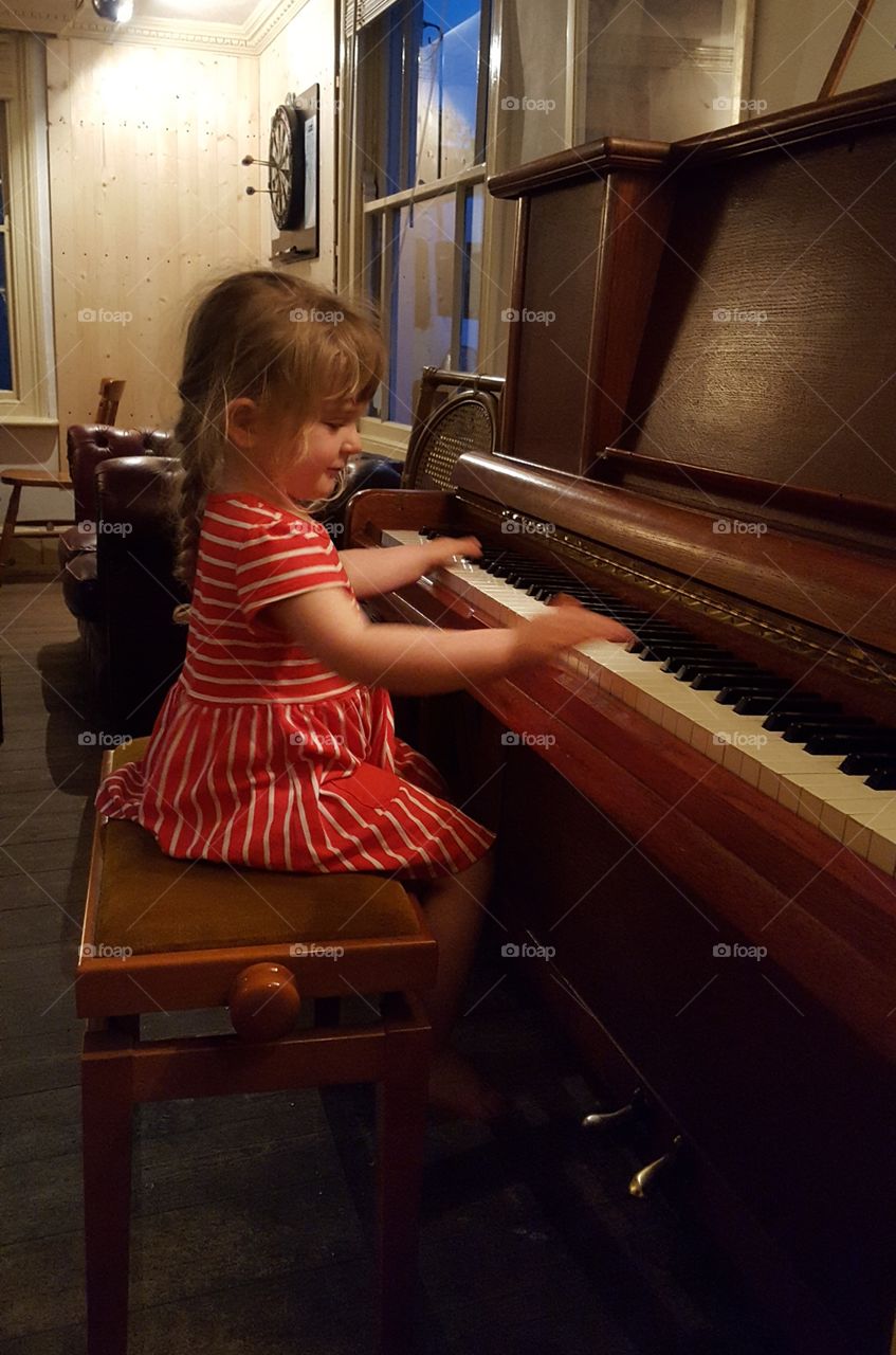 Three Year Old Girl Playing Piano in English Pub.