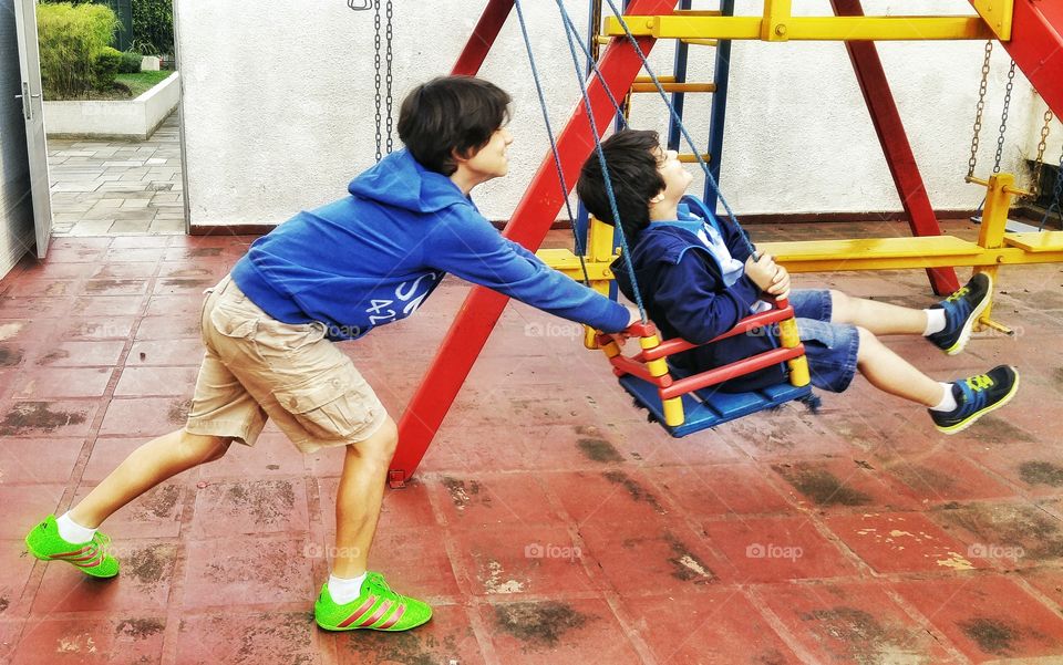 Boys playing with swing in the playground