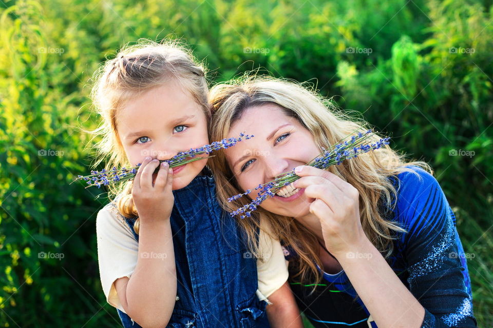 Portrait of mother and daughter holding plant on face