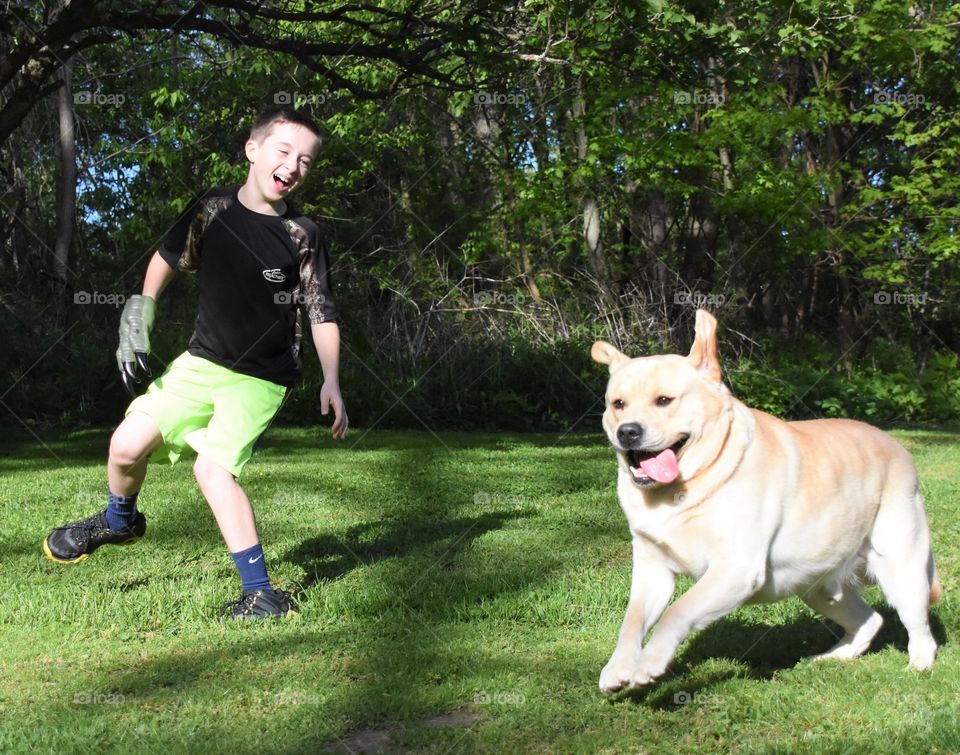 Boy outside running and playing with a yellow Labrador 