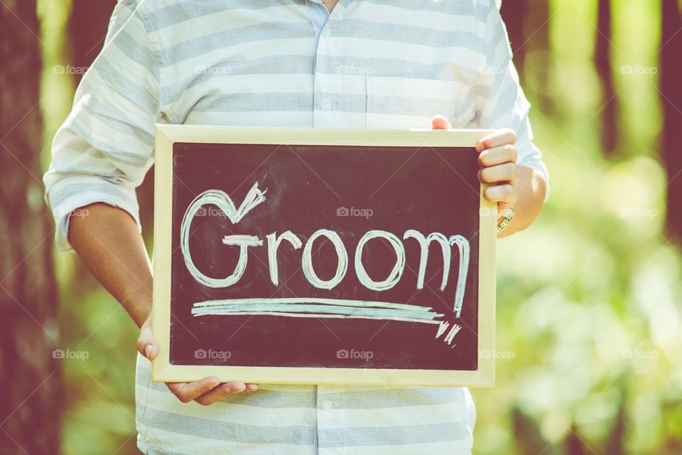 A man holds a poster board groom