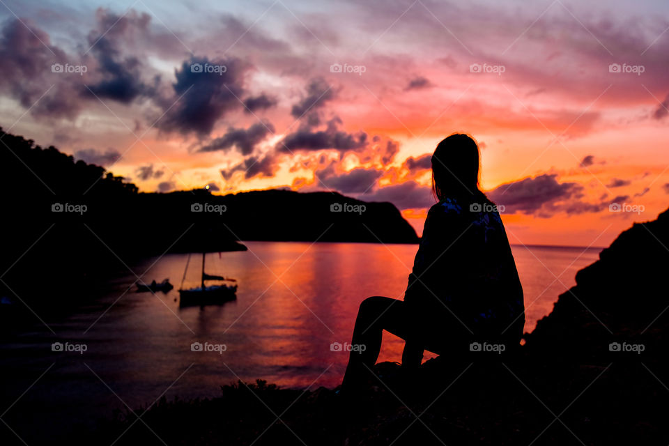 Silhouette of a person sitting on cliff