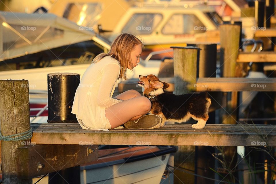 Girl with her dog sitting on a bridge