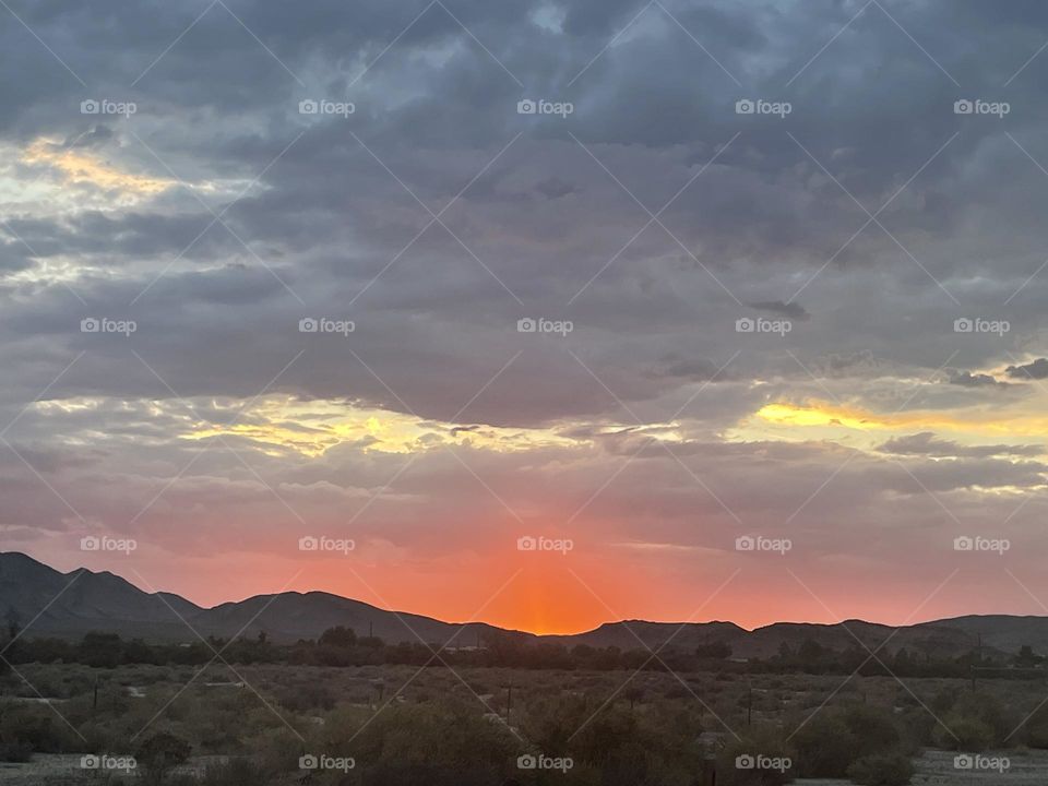 A red and pink sunset with clouds and mountains.