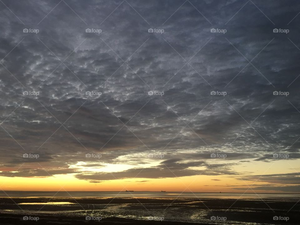 Heavy dark clouds and storm system over sunset at ocean 