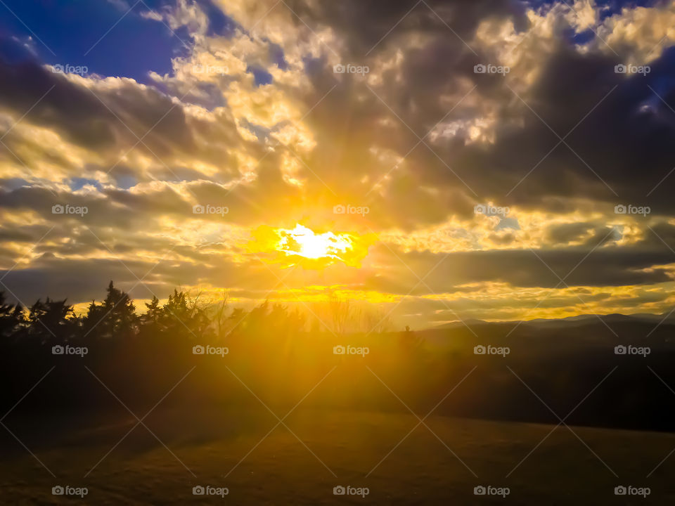 Magnificent sunset through cotton ball clouds over a wonderful mountain setting