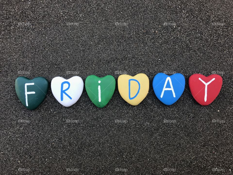 Friday, day of the week with multicolored heart stones over black volcanic sand 