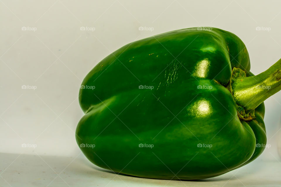 fresh green bell pepper (capsicum) on a white background.