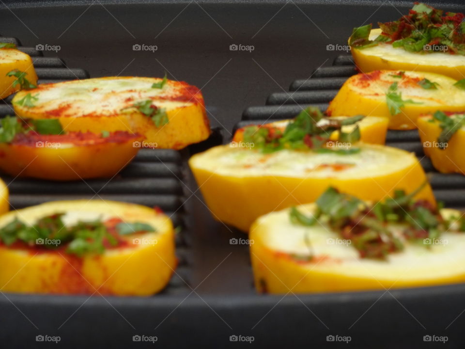 Yellow zucchini on grill with paprika and basil - yellow/red/green on black
