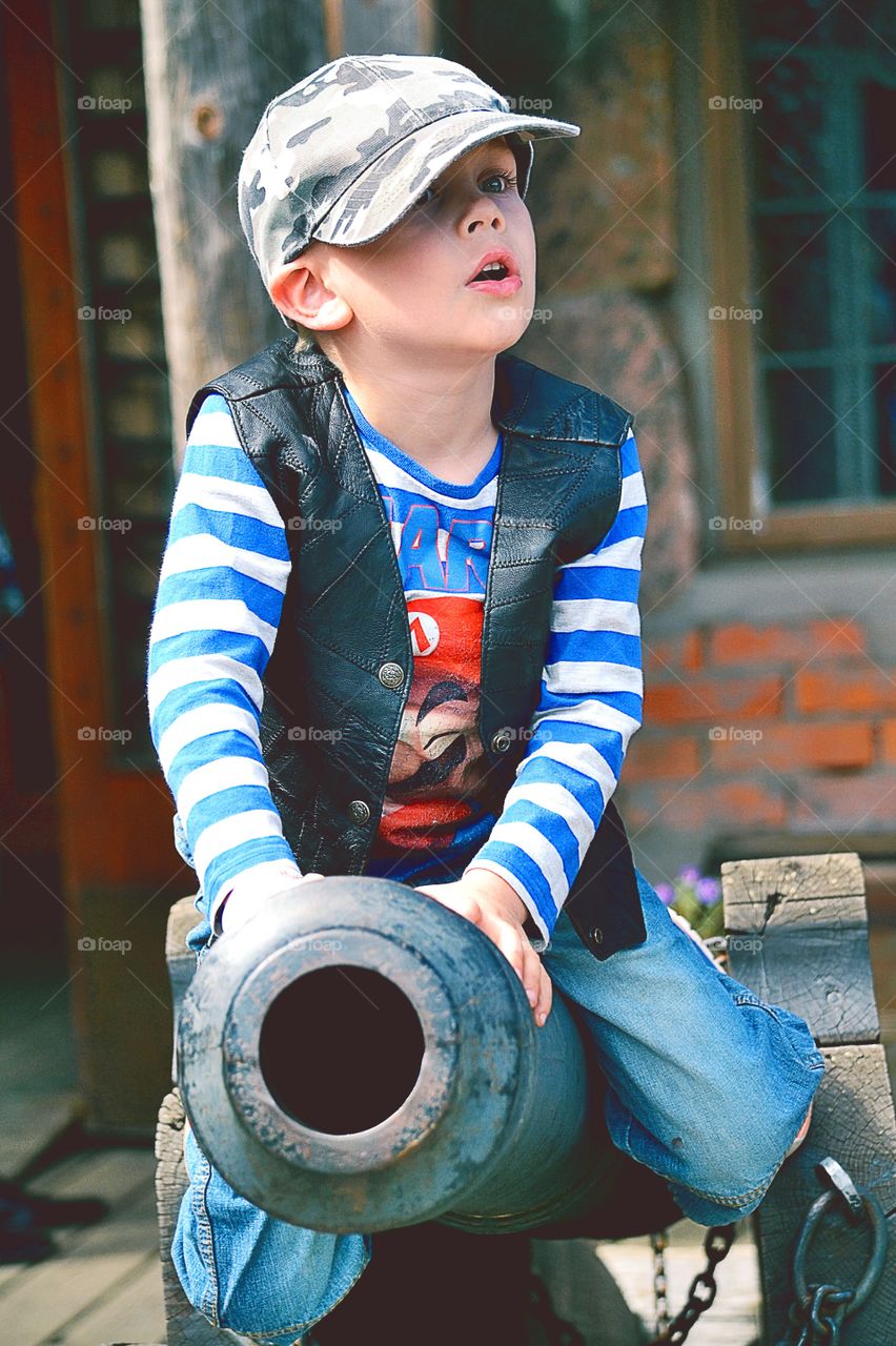 Boy sitting on a canon