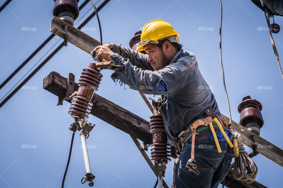 Electrician working on the electricity pole to replace the electrical insulator