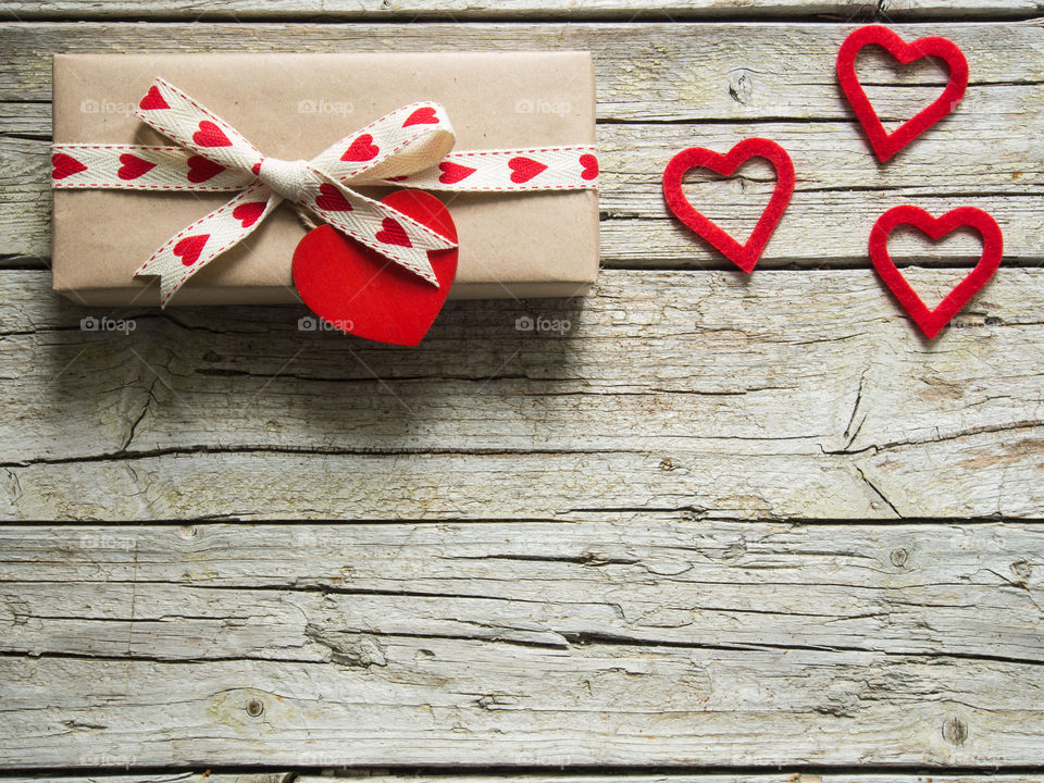 Valentine gift box and red heart shapes on vintage wooden background 