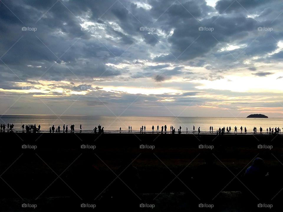 sunset view,people standing like fence at beach
