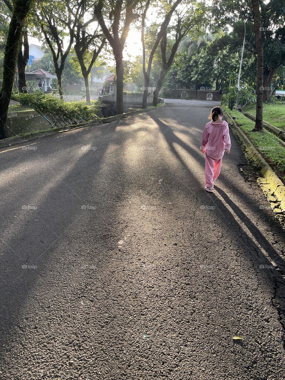 Little girl joging at house compund in beautiful sunrays and trees around