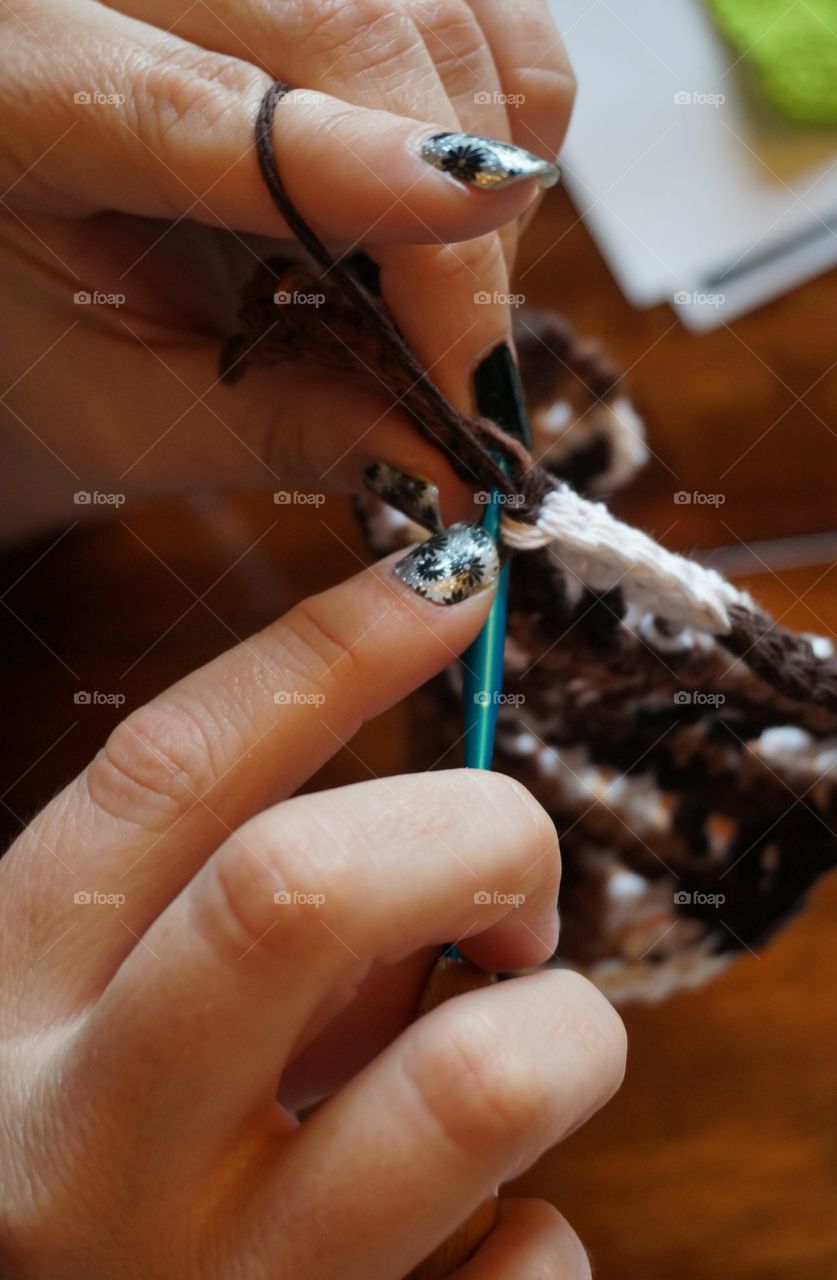 Hands working with yarn and needle