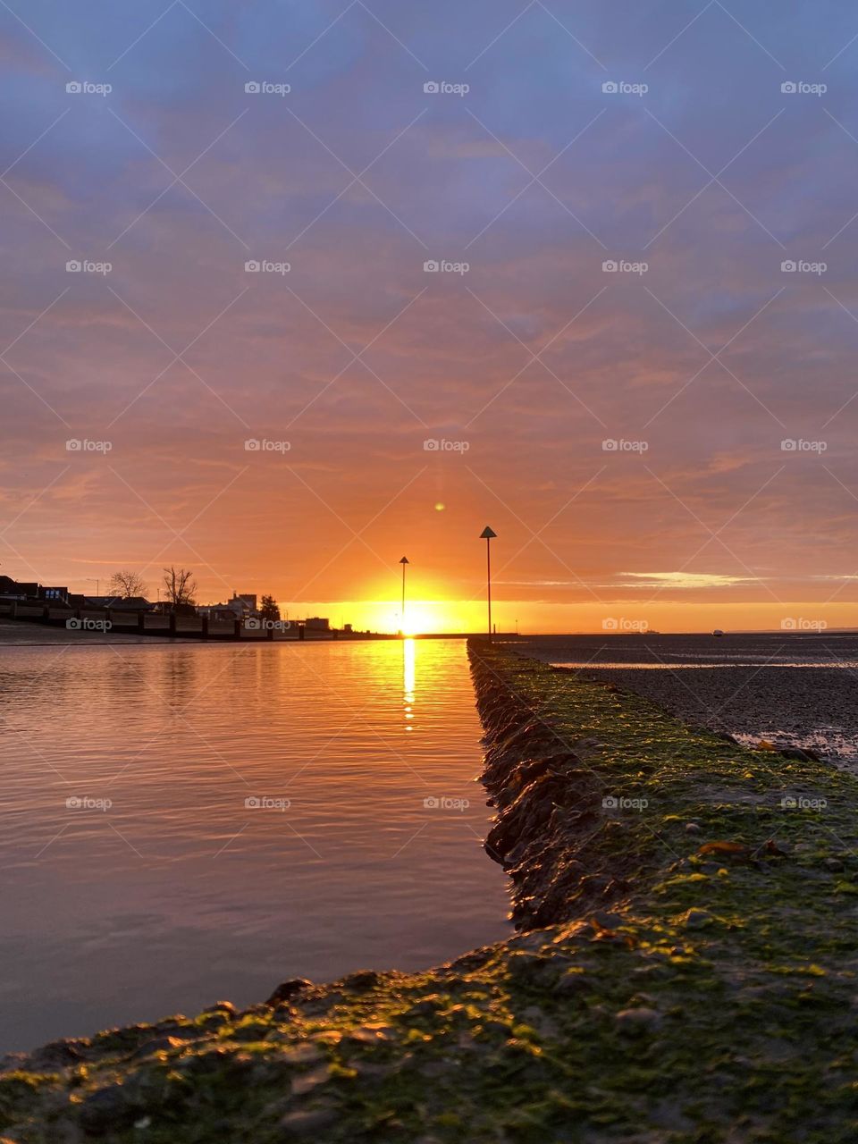Warm beach sunrise scene with reflections on the water 