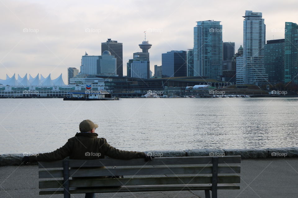 Man on the beach looking in the city on the other side of water