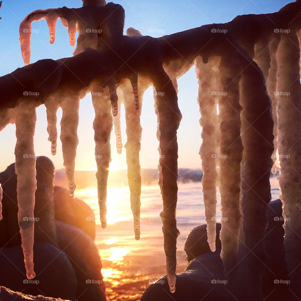 Frozen sunrise// sunrise seen from behind icicles hanging from tree branches 