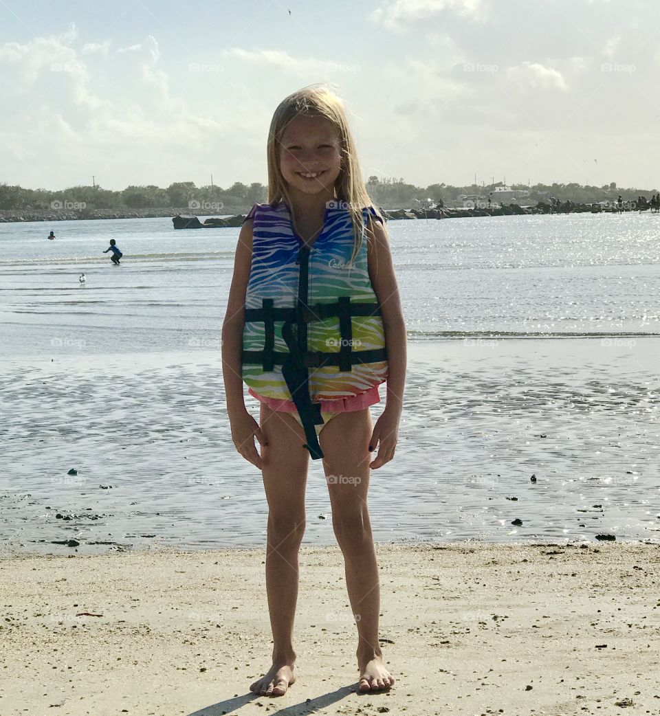 Girl at beach in life jacket