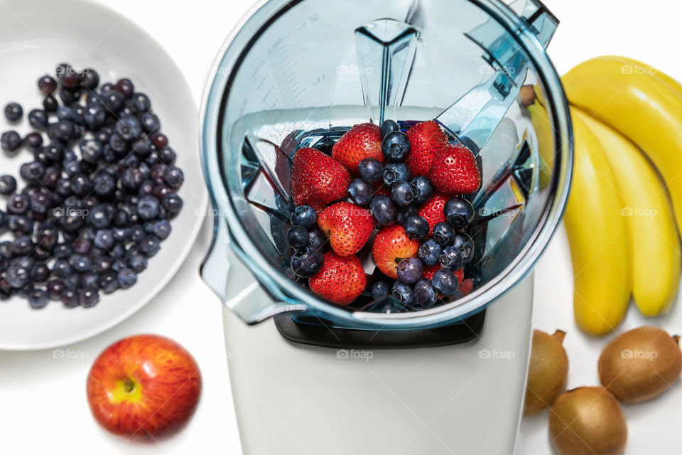 Series of shots. Photo 6. Blender in a top view, with ingredients for a smoothie. In this series we add strawberries and blueberries in an empty blender and bananas, kiwi, apple, sprouts on the table