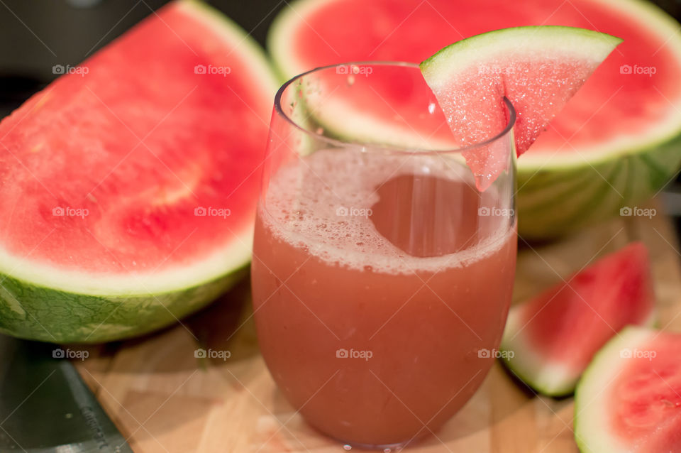 Homemade pretty pink watermelon juice cocktail garnished with juicy sliced seedless watermelon for refreshing summer party or easy to make healthy drink idea or garden party background 