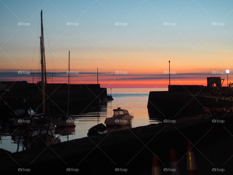 Vibrant sunset over Aberaeron Harbour with silhouettes of boats